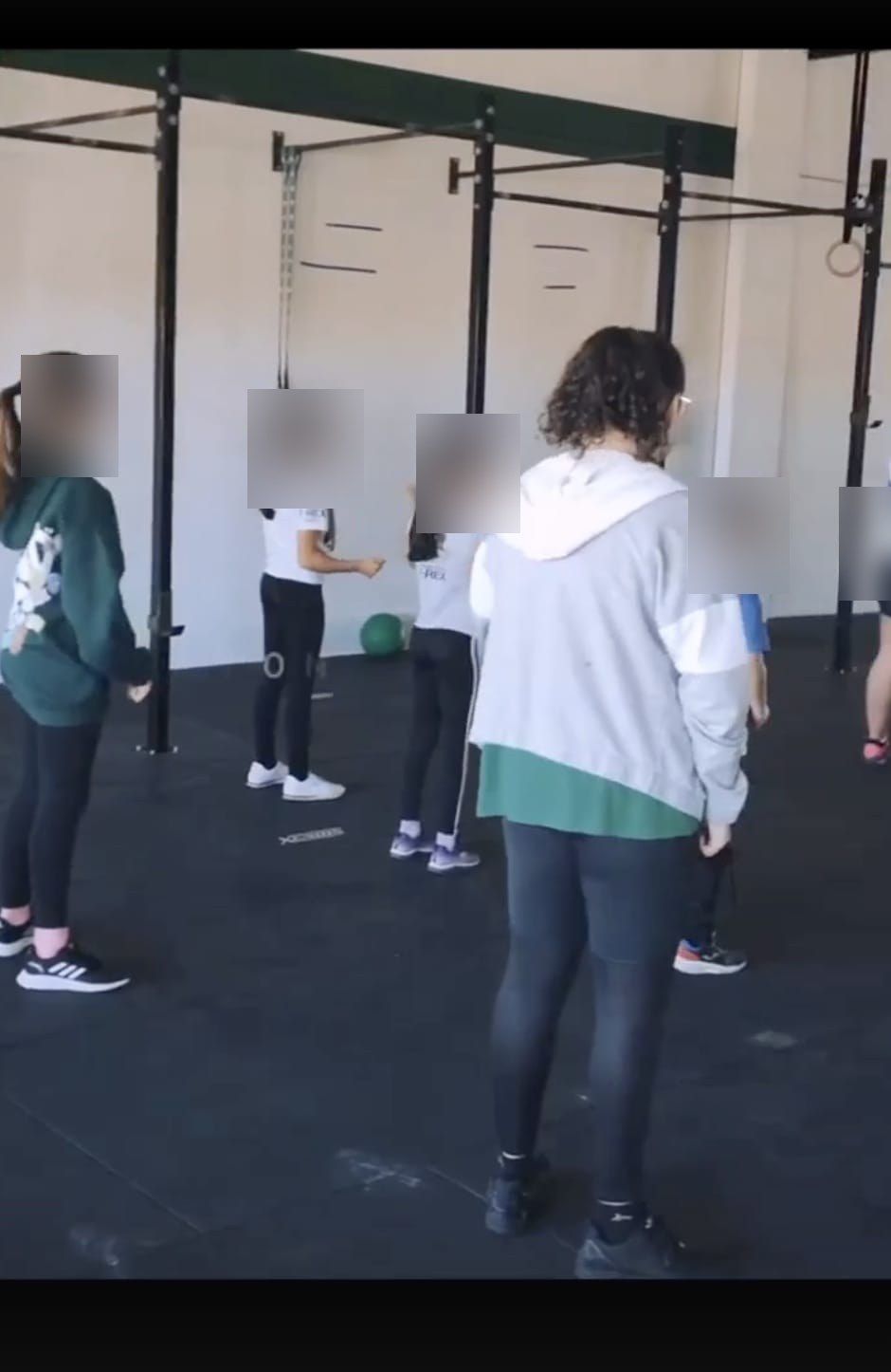 Grupo de niños atendiendo a la explicación de la coach en la clase de CrossFit Kids