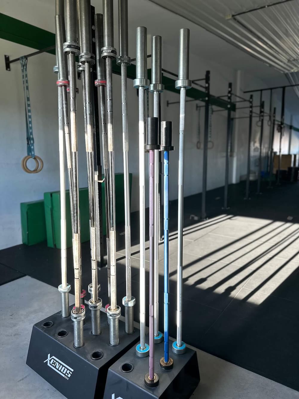 Barras olímpicas colocadas en su soporte junto a la pared