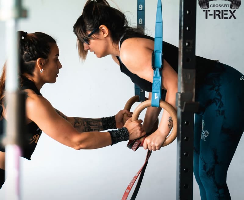Una coach sujetando las anillas mientras otra socia hace el ejercicio